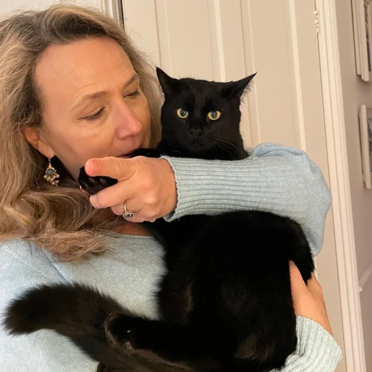 Ägare som varsamt håller en svart katt i famnen